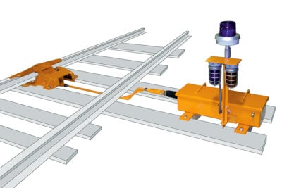 A detailed rendering of the Automated Derail Operator. The Derailer is fastened to one side of the railroad track and is attached to a cord that runs underneath the rail track. The cord is attached on the other side of the track to an assembly that will automatically shift the derailer on and off the track.