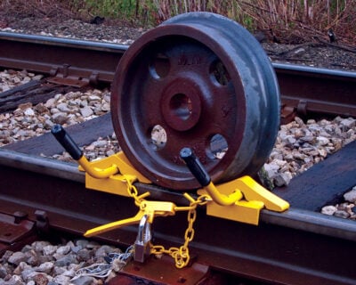 A wheel chock set holds a train wheel in place along a train track